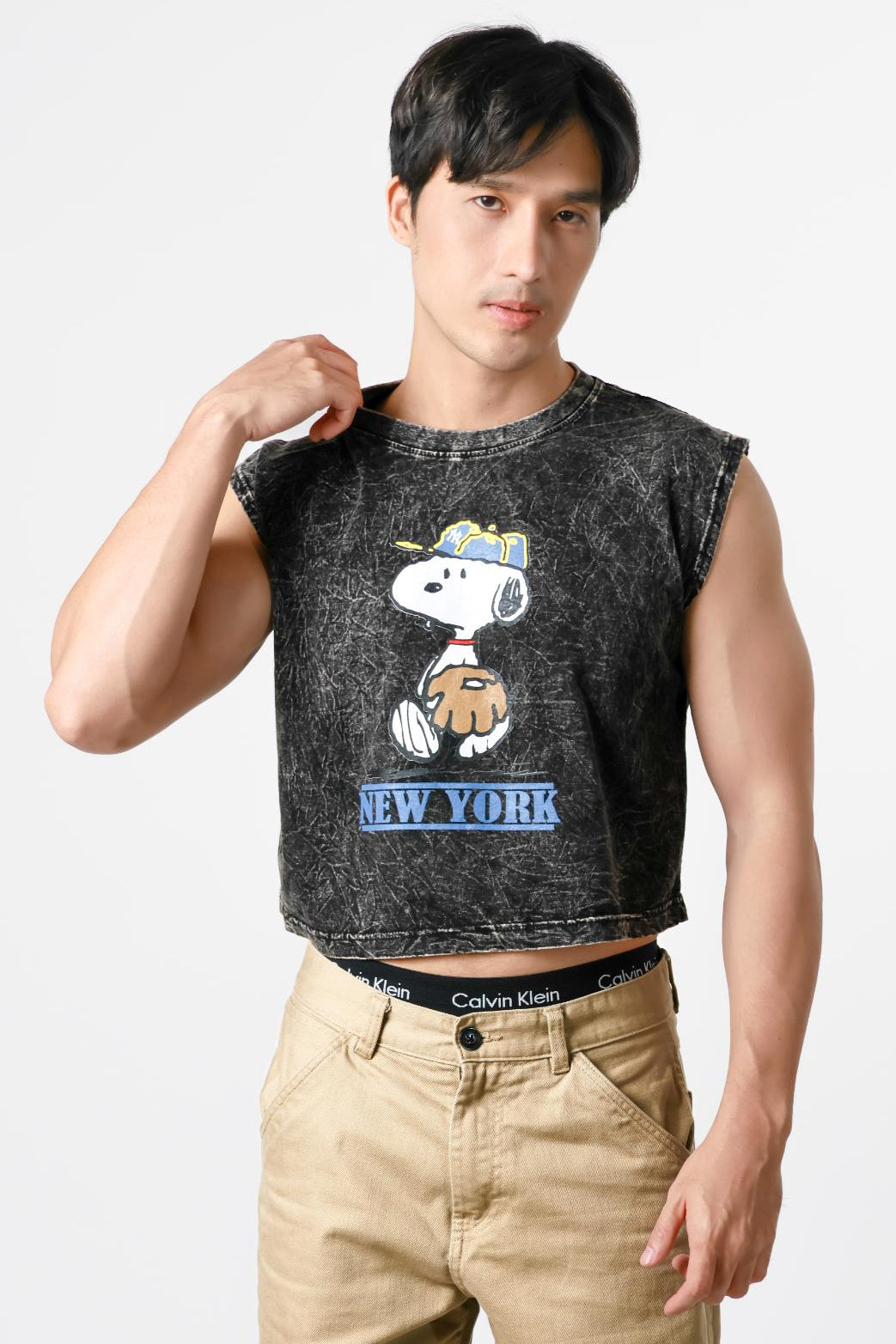 Man wearing a sleeveless shirt with a cartoon character design on a plain background